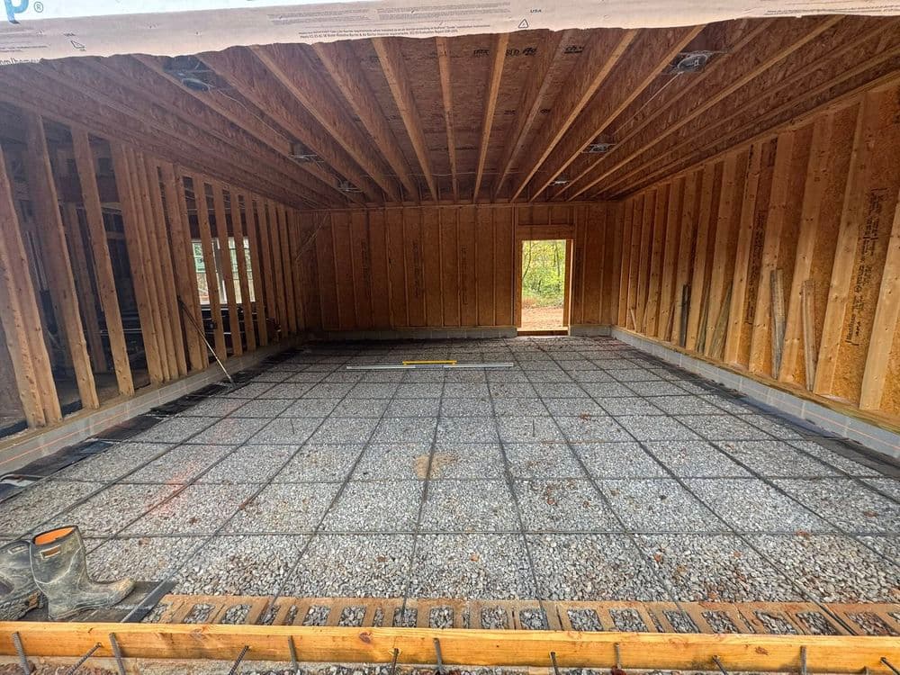 Interior view of a house under construction with exposed framing and gravel floor.