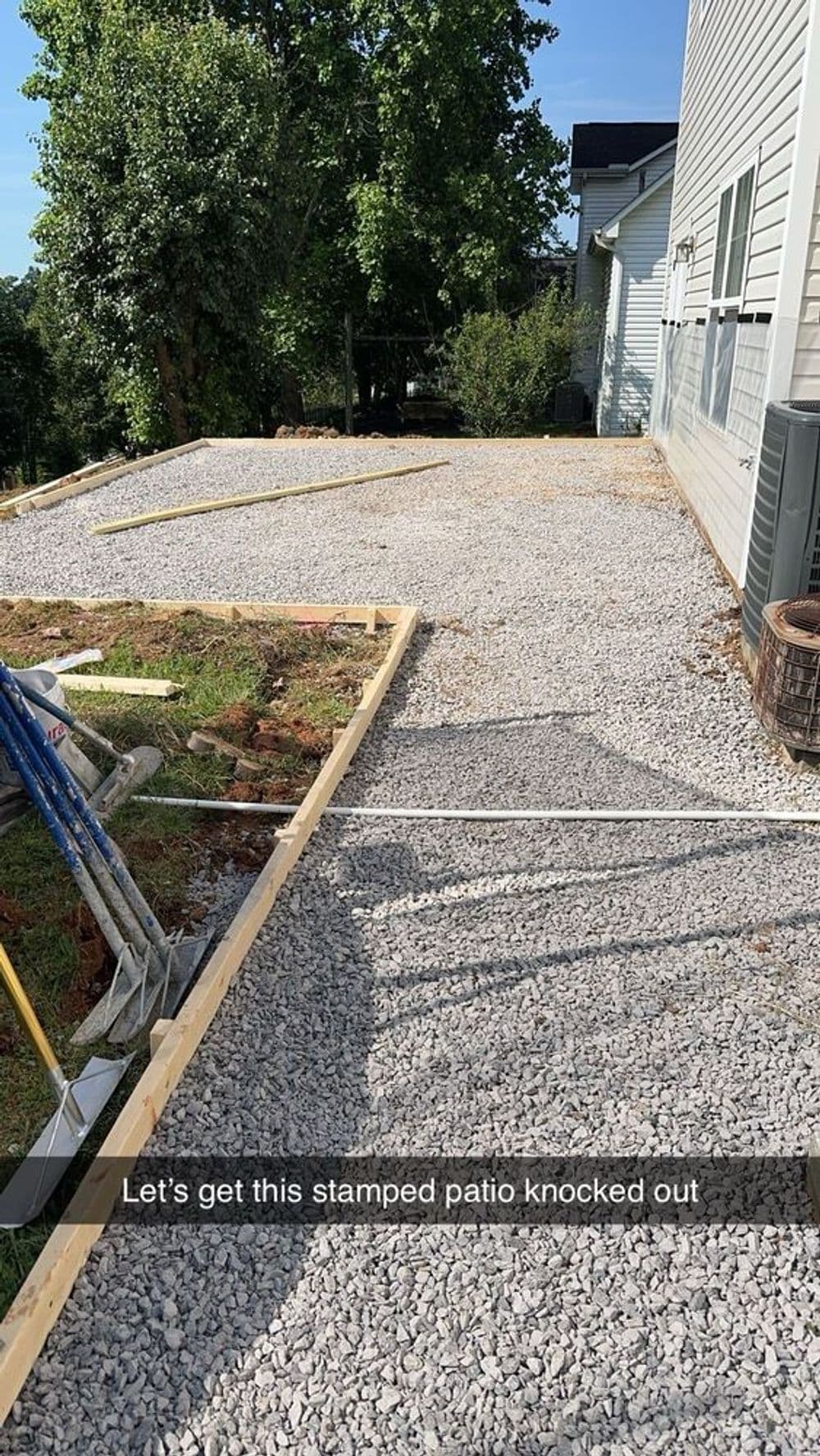 Gravel patio preparation for stamped concrete installation beside a house.